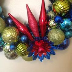 a christmas wreath with red, green and blue ornaments hanging from it's sides