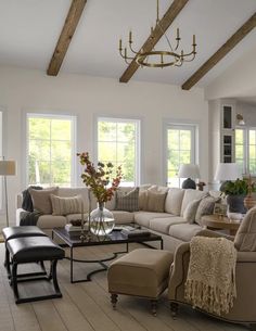 a living room filled with lots of furniture next to two windows and a chandelier