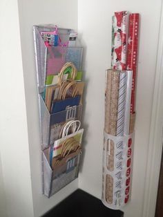 there is a small storage rack on the wall next to some rolls of wrapping paper