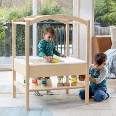 two children playing in a wooden play table