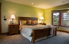 a bed room with a neatly made bed and two lamps on either side of the bed