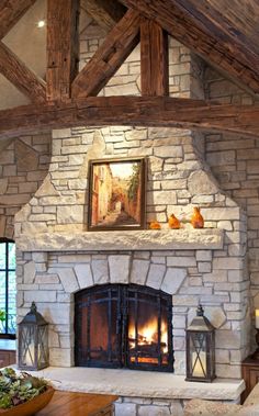 a living room with a stone fireplace and wooden beams