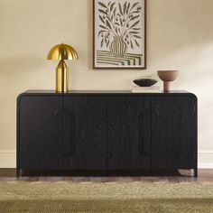 a black and gold sideboard in a living room with a painting on the wall