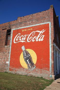 an old coca - cola advertisement painted on the side of a building in black and white