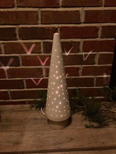 a white light up christmas tree sitting on top of a wooden table next to a brick wall