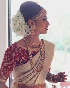 a woman in a red and white sari with flowers on her head, wearing jewelry