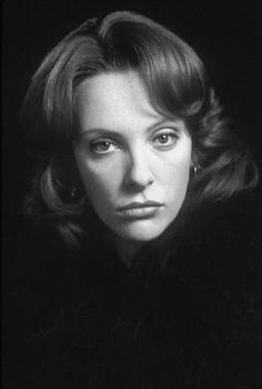 black and white photograph of a woman in fur collared coat looking at the camera