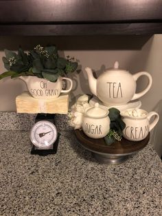 there is a clock and tea set on the counter