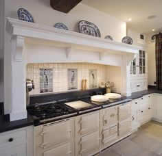 a kitchen with white cabinets and black counter tops is pictured in this image, there are plates on top of the stove