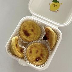 four small pastries in a plastic container on a white table top with a yellow sticker