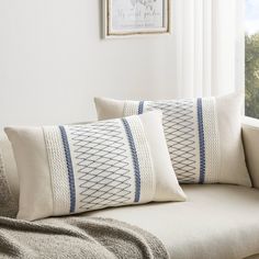 two pillows sitting on top of a couch next to a window