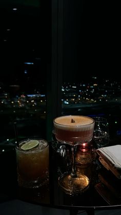 a table topped with two glasses filled with liquid next to a candle on top of a table