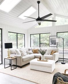 a living room with white couches and large windows in the ceiling is filled with natural light