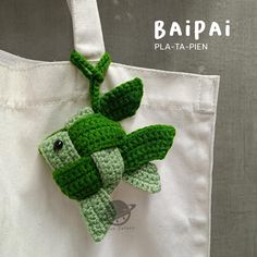 a crocheted bag with a green frog on it's back hanging from a hook