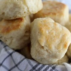 some biscuits are sitting in a basket on a checkered table cloth and is ready to be eaten