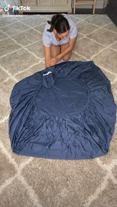 a woman kneeling down on the floor with a blue cover over her face and knees