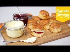 some food is sitting on a cutting board next to a jar of jam and butter