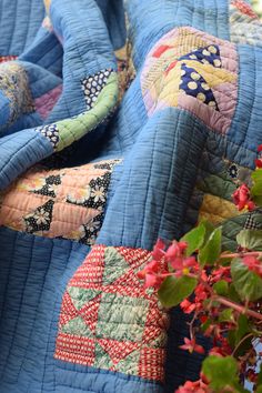 a close up of a blue quilt with flowers in the background