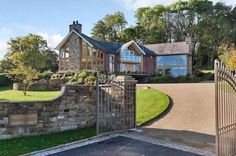 a large house with a driveway and gated in area next to the road that leads to it