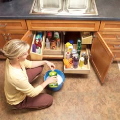 a woman kneeling down in front of an open cabinet