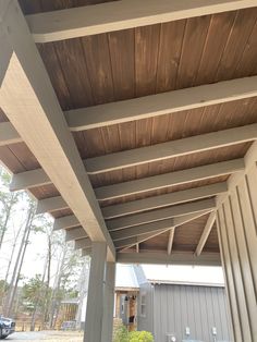 an outdoor covered patio area with wooden roofing and white siding on the side of it