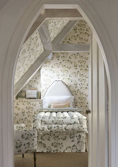 an arched doorway leading to a bedroom with floral wallpaper and bed in the corner