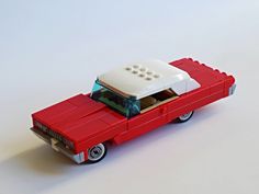 a red and white toy car sitting on top of a table