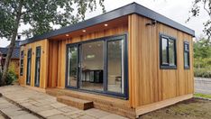 a small wooden building sitting in the middle of a yard with lots of windows and doors