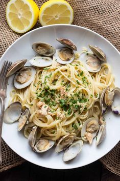 a plate of pasta with clams and lemon slices