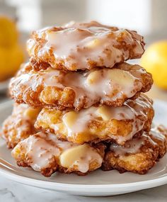 a stack of glazed donuts sitting on top of a plate next to lemons