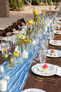 a long table set with plates and vases