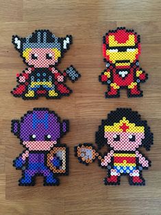 four different pixel art pieces on a wooden surface, each with one character in the middle