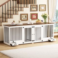 a white dog crate sitting on top of a wooden floor next to a stair case