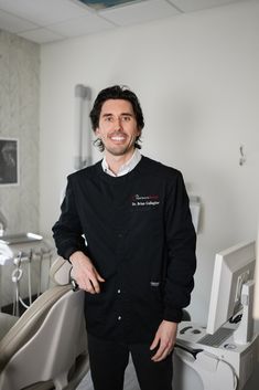 a man standing in front of a dental chair with his hands on his hips and smiling at the camera