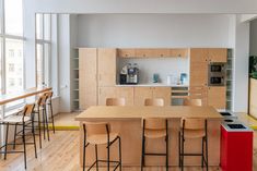 an open kitchen and dining room area with wooden cabinets, bar stools, counter tops, and hardwood flooring