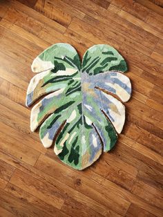 a green and blue rug with a monster plant on it's side sitting on a wooden floor