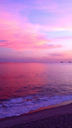 an ocean beach with waves coming in to shore and the sun setting over the water