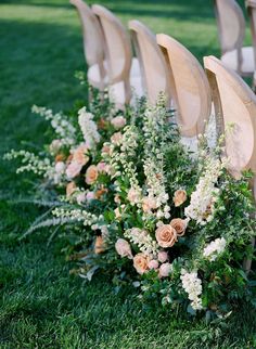 rows of wooden chairs with flowers and greenery