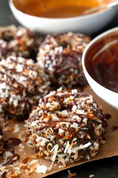 chocolate covered donuts sitting on top of a wooden cutting board next to a bowl of dipping sauce