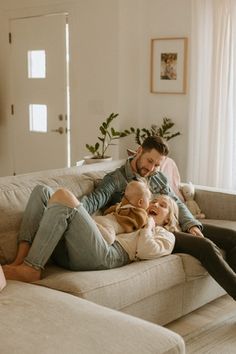 a man and two women sitting on top of a couch next to each other in a living room