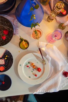 a table topped with plates and bowls filled with desserts next to drinks on top of a white table cloth