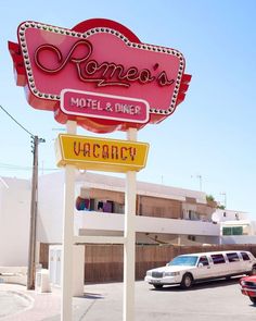 a sign for a motel and diner in front of a parking lot with parked cars