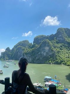 a woman looking out over the water at boats