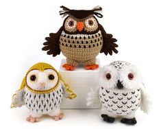 three small crocheted owls sitting on top of each other in front of a white background