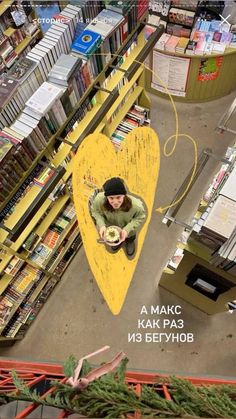 a man sitting on top of a wooden bench in a book store filled with books