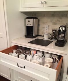 an open drawer in a kitchen filled with coffee cups