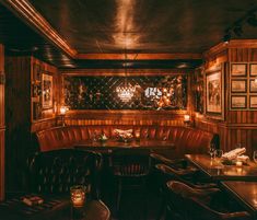 a dimly lit restaurant with wood paneling and leather booth seating, along with pictures on the wall