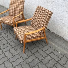 two chairs sitting next to each other on the ground near a wall and cement floor