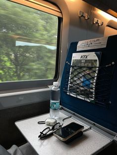 the inside of a train car with an open window and water bottle on top of it