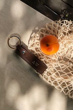 an orange sitting on top of a bag next to a keychain